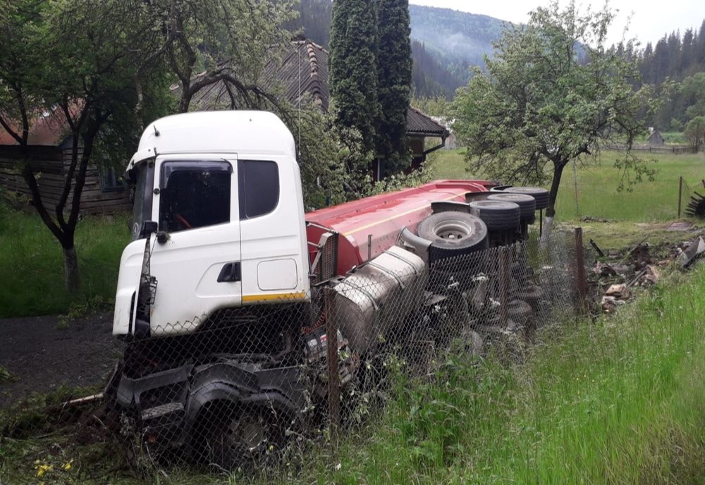 FOTO. Accident grav la Corbu. Bărbat lovit în fața porții de un camion răsturnat peste gard, în urma impactului cu un alt camion